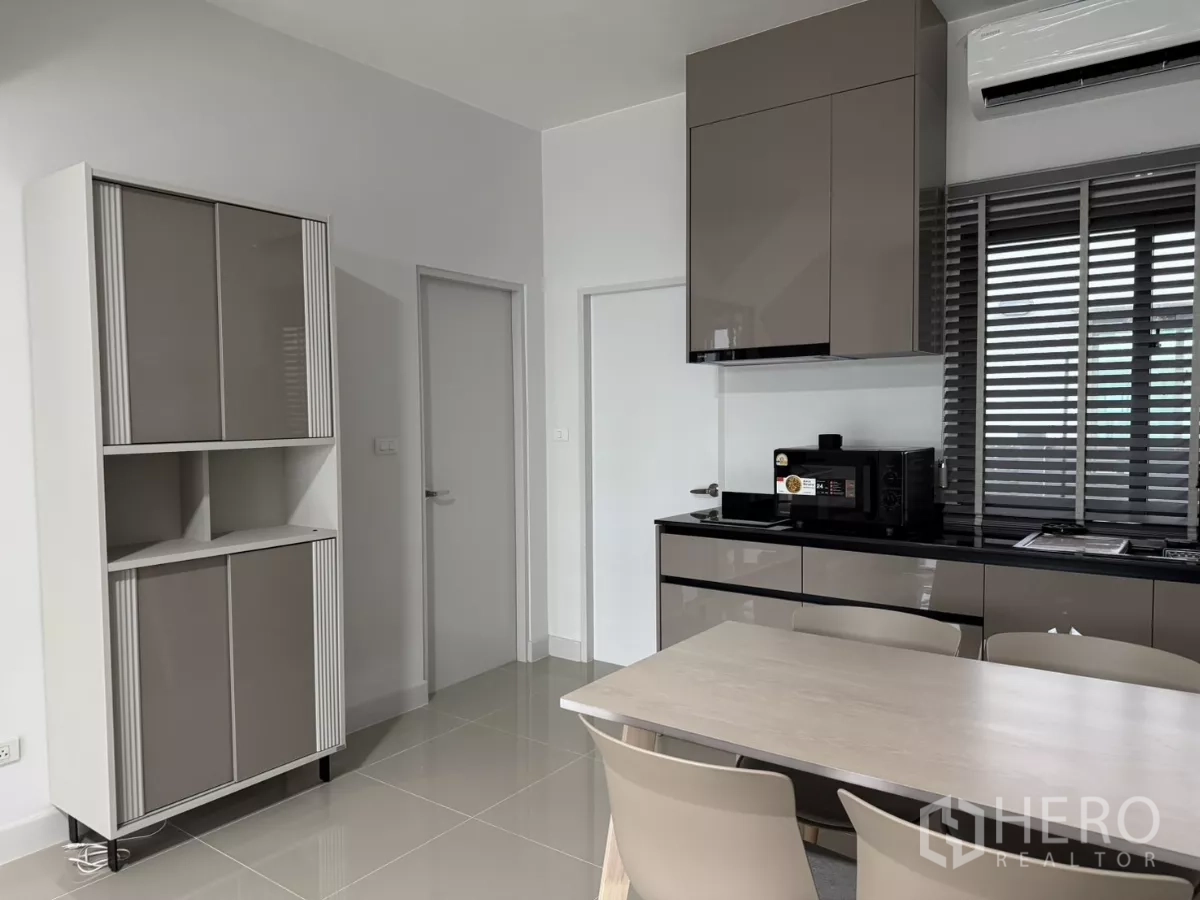 Townhouse for rent in Bang Phli, Samut Prakan - Built-in kitchen storage and pantry beside the dining area in neutral tones.