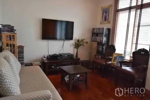 Detached House for sale in Bueng Kum, Bangkok - Cozy family room with wall-mounted TV, media console, wood floors and windows with blinds.