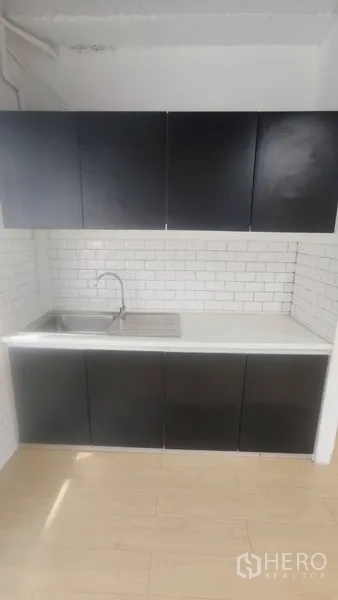 办公空间 出租在Pathum Wan, Bangkok - 茶水间，黑色橱柜，不锈钢水槽与白色地铁砖墙面。