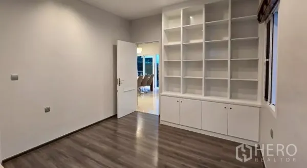 Detached House for rent in Samut Prakan - Multipurpose room with built-in white shelving and wood floors.