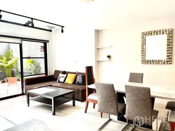 Townhouse for rent in Khlong Toei, Bangkok - Open living and dining space with sectional sofa and dining table beside the terrace.