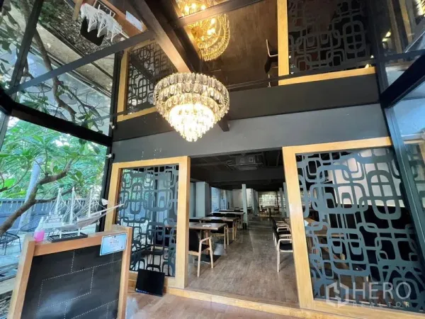 零售空间 出租在Bangkok - 玻璃挑空门厅，水晶吊灯与几何隔断，通向用餐区。