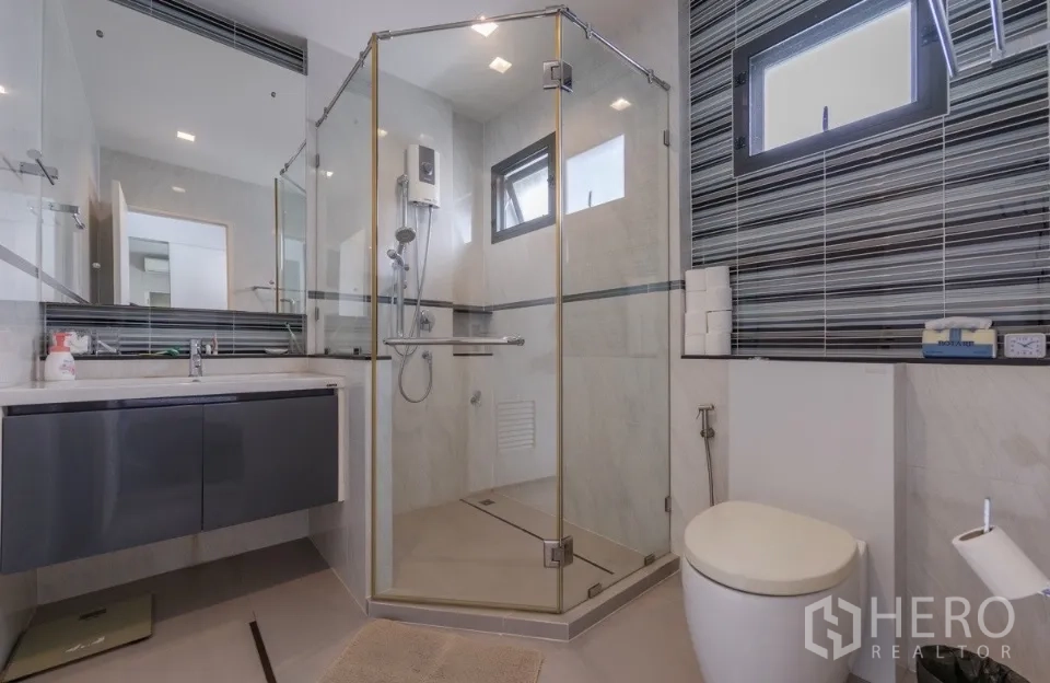 Detached House for rent or sale in Bang Kapi, Bangkok - Contemporary bathroom with glass shower and sleek vanity.
