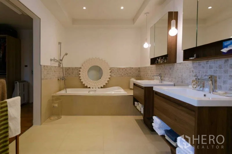 Home Office for sale in Watthana, Bangkok - Bathroom with bathtub, twin vanities and soft pendant lighting beside tiled walls.