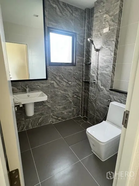 Detached House for rent or sale - Contemporary bathroom with gray stone-look tiles, wall-mounted sink, shower corner and window.