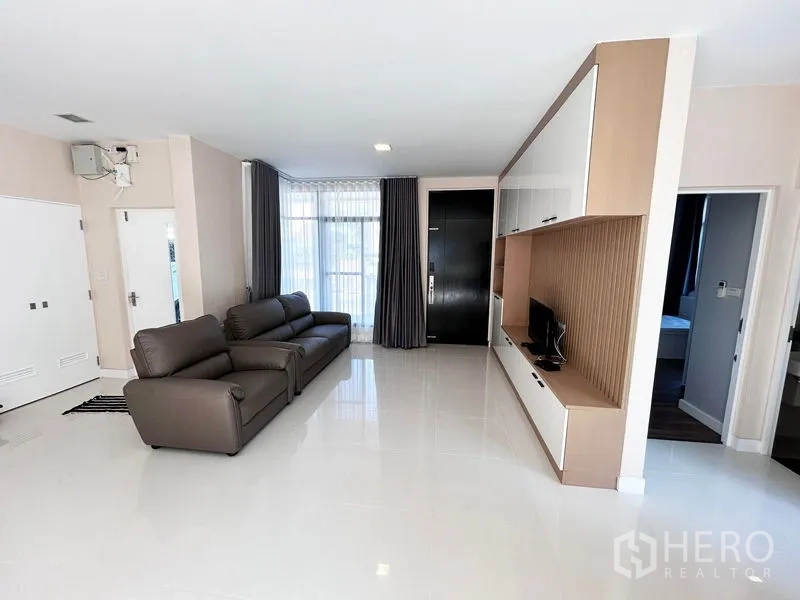 Detached House for rent or sale in Prawet, Bangkok - Bright living room with leather sofas and built-in TV cabinet.