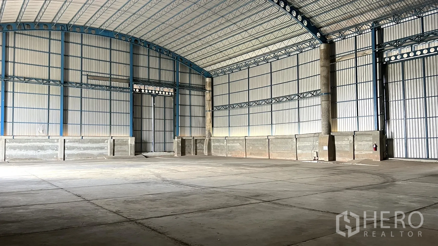 Warehouse for rent in Ban Pho, Chachoengsao - Spacious warehouse interior with high arched roof, steel trusses and smooth concrete floor.