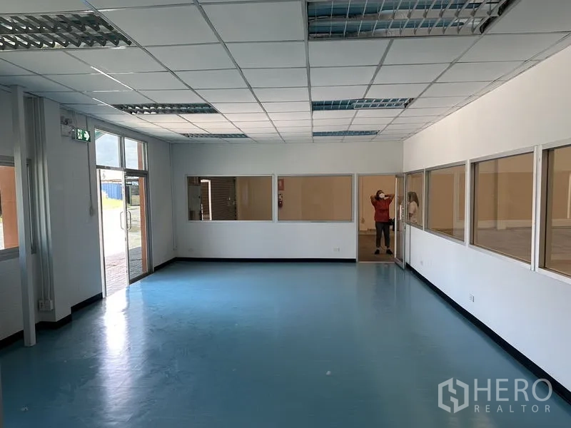 Factory for rent in Bang Phli, Samut Prakan - Side service door and walkway lined with trees beside the factory building.