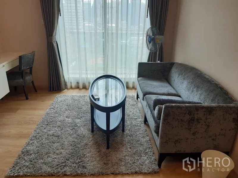 Condominium for rent or sale in Watthana, Bangkok - Cozy seating area by a large window with city view, rug and curtains.