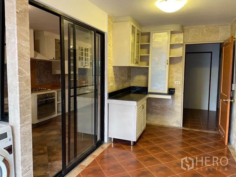 คอนโด ให้เช่าในWatthana, Bangkok - ประตูกระจกบานเลื่อนกั้นโซนซักล้างกับครัวตกแต่งผนังหิน เคาน์เตอร์สีดำ