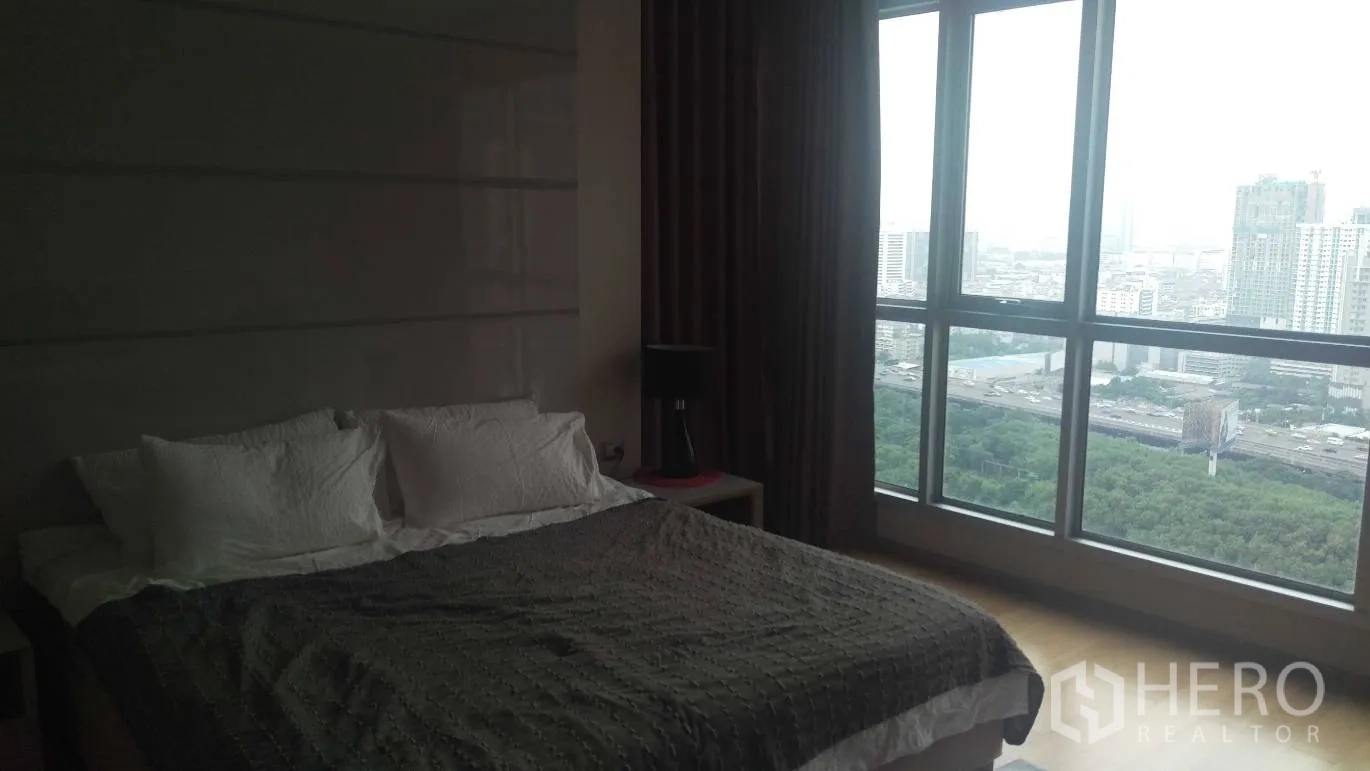 Condominium for rent in Ratchathewi, Bangkok - Master bedroom with large bed and panoramic city view through floor‑to‑ceiling windows.
