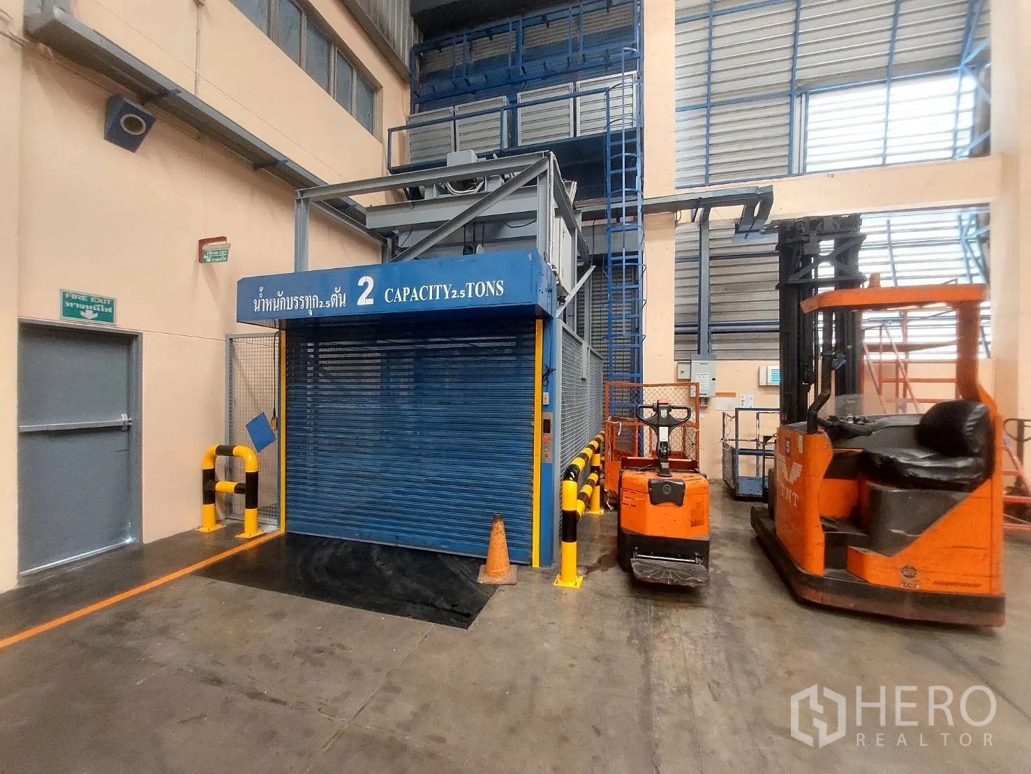货栈 出租在Mueang Pathum Thani, Pathum Thani - 2.5 吨货运电梯，旁有叉车与安全出口门。