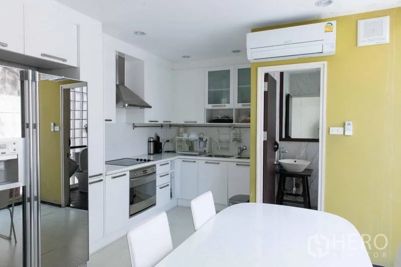 联排别墅 出售 - 现代白色厨房，餐桌、嵌入式烤箱及通往盥洗室的门。