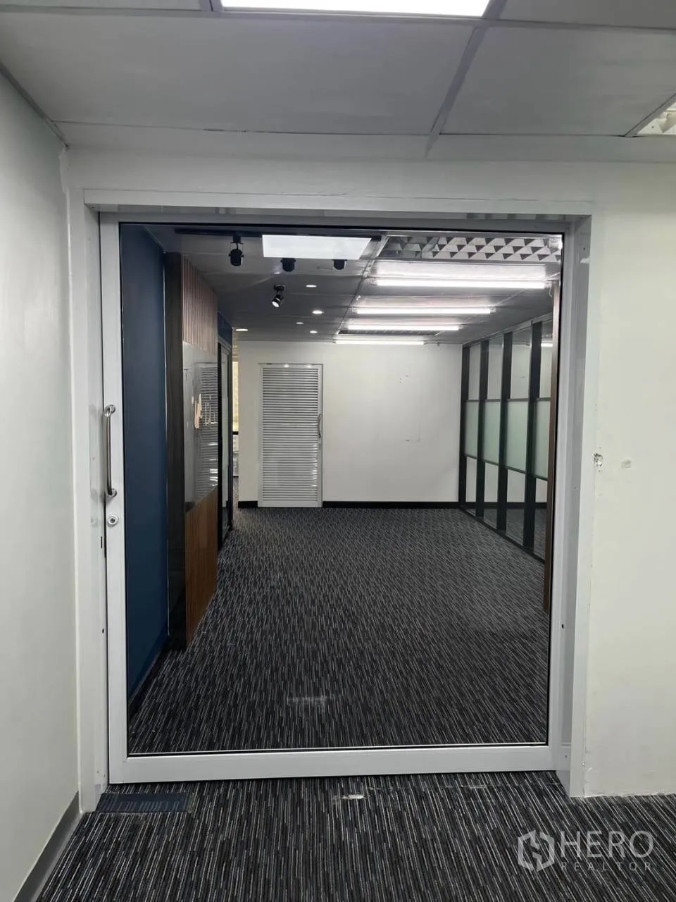 Office Space for rent in Khlong Toei, Bangkok - Glass entry door opening to a carpeted office with ceiling lights and internal partitions.