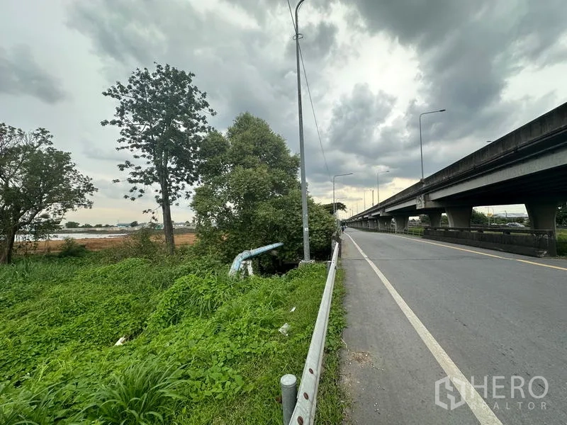 ที่ดิน ขายในSai Mai, Bangkok - ถนนเลียบทางยกระดับ มีต้นไม้ ท่อระบายน้ำ และท้องฟ้าครึ้ม ใกล้แปลงที่ดินว่างในสายไหม