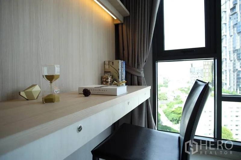 Condominium for rent in Khlong Toei, Bangkok - Close-up of a window-side work desk with books and decor overlooking the city.