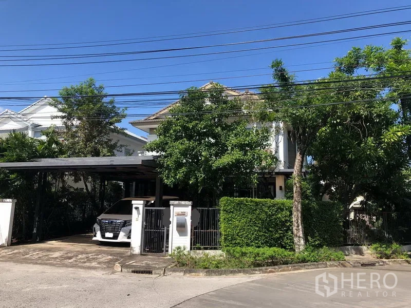 Detached House for rent or sale in Bang Kapi, Bangkok - Two-storey detached house with gated entrance, covered carport and mature trees in a quiet estate.
