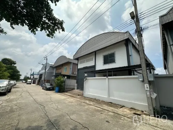 工厂 出租在Bang Bua Thong, Nonthaburi - 安静工业巷道中的一排小型工厂，路边可停车并有电线杆。