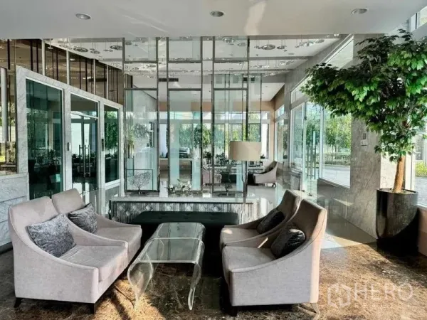 公寓 出售在Ratchathewi, Bangkok - 公寓大堂休息区，布艺沙发、玻璃隔断与绿植景观。