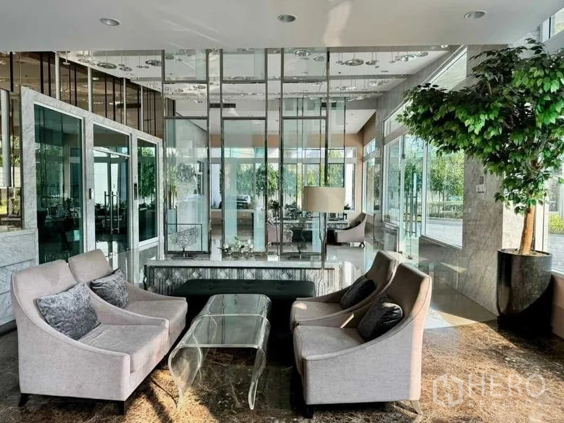 公寓 出售在Ratchathewi, Bangkok - 公寓大堂休息区，布艺沙发、玻璃隔断与绿植景观。