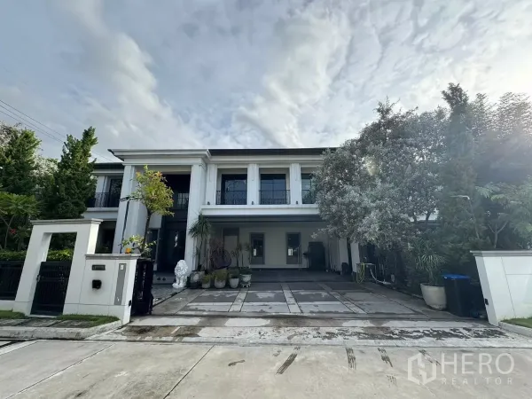 独立式住宅 出售在Mueang Pathum Thani, Pathum Thani - 两层豪华独栋住宅外观，挑高立柱、车道与景观树。