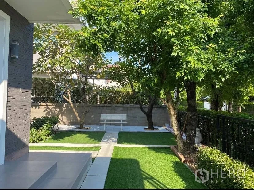 独立式住宅 出租或出售在Prawet, Bangkok - 前庭景观花园，大树、长椅与铺装步道。