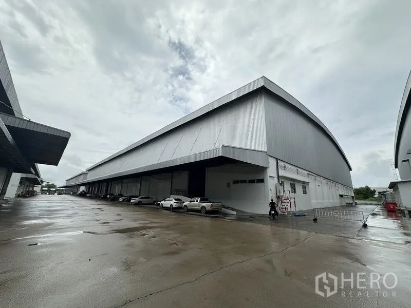 货栈 出租在Phra Nakhon Si Ayutthaya - 金属板外墙的大型仓库与带顶装卸月台及宽阔硬化场地的全景。