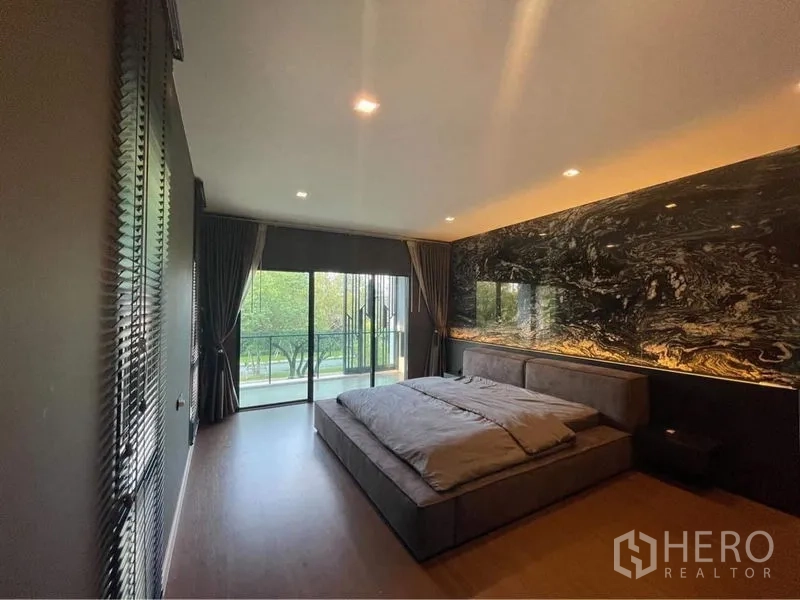 Detached House for rent or sale in Bang Phli, Samut Prakan - Spacious master bedroom with dark marble feature wall and balcony access.