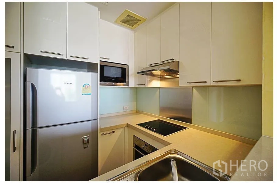 公寓 出售在Watthana, Bangkok - U形厨房，白色橱柜，内置烤箱与电炉，抽油烟机、微波炉及不锈钢冰箱。