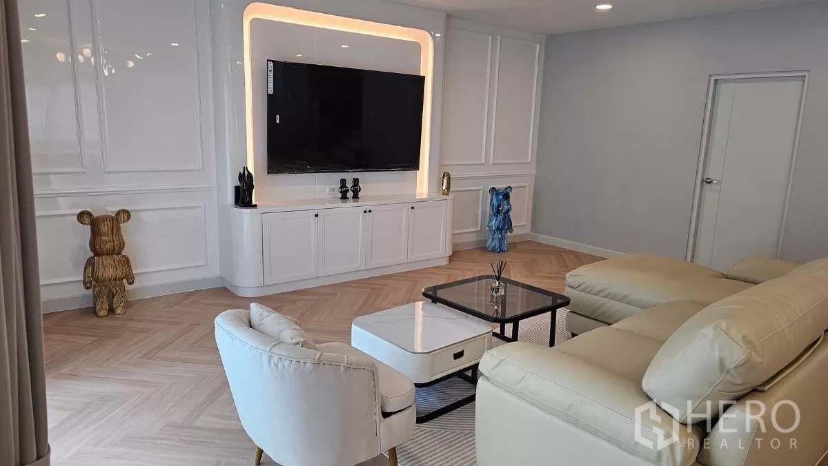 Detached House for rent or sale in Bang Phli, Samut Prakan - Feature TV wall with built-in cabinetry and LED lighting opposite a cream sofa in the living room.