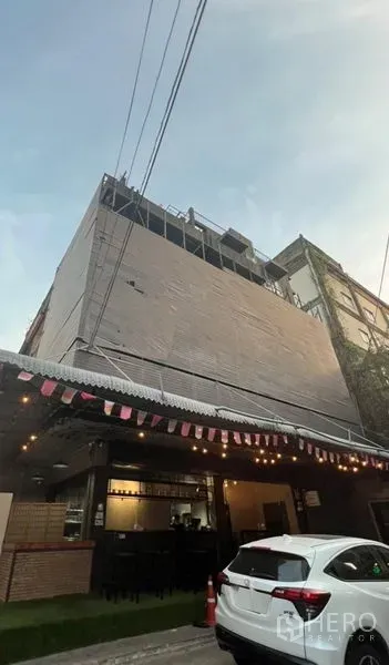 อาคารพาณิชย์ ให้เช่าหรือขายในWatthana, Bangkok - อาคารพาณิชย์หลายชั้นพร้อมชั้นล่างสไตล์คาเฟ่ หลังคากันสาดและไฟประดับบนถนนเมือง