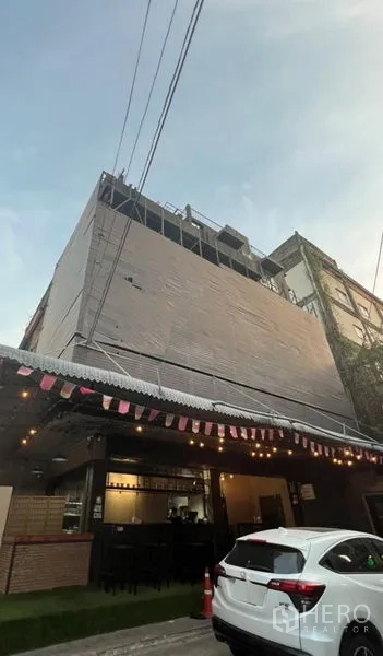 อาคารพาณิชย์ ให้เช่าหรือขายในWatthana, Bangkok - อาคารพาณิชย์หลายชั้นพร้อมชั้นล่างสไตล์คาเฟ่ หลังคากันสาดและไฟประดับบนถนนเมือง