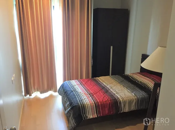 Condominium for rent in Watthana, Bangkok - Cozy bedroom with single bed, wardrobe, and floor‑to‑ceiling curtains filtering natural light.