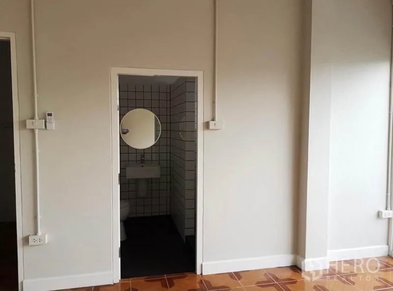 联排别墅 出租或出售在Din Daeng, Bangkok - 卧室内卫浴入口，方砖墙与圆形镜。