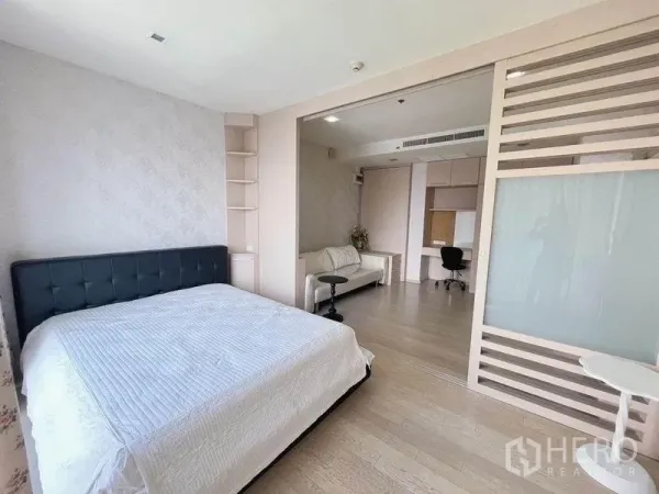 Condominium for sale - Spacious master bedroom opening to a study area via sliding partition, with built-in shelving and a sofa.