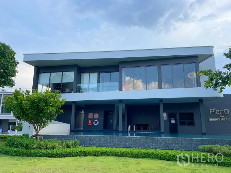Townhouse for rent in Bang Phli, Samut Prakan - Modern clubhouse with fitness center and glass facade overlooking lawn.