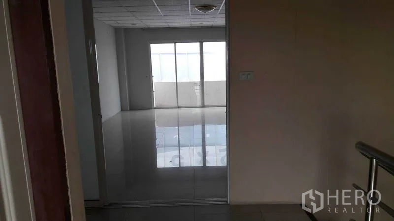 Office Space for rent in Bueng Kum, Bangkok - Hallway view into a sunlit office with glossy tile floor and balcony doors.