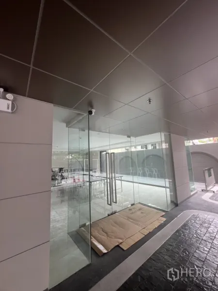 零售空间 出租在Watthana, Bangkok - 现代天花下的双开玻璃门入口，配备监控摄像头。