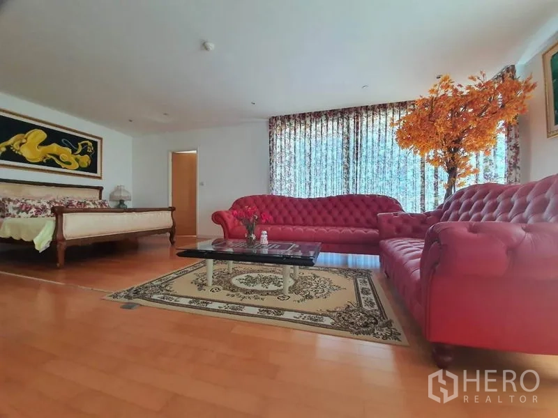 คอนโด ขายในWatthana, Bangkok - พื้นที่นั่งเล่นเปิดโล่ง โซฟาสีแดงเข้าชุด ผ้าม่านลาย พื้นไม้ และมีเตียงในมุมมอง