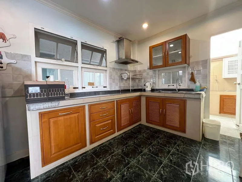 Detached House for rent in Bang Phli, Samut Prakan - U-shaped western kitchen with wooden cabinetry, stone countertops, and cooker hood.