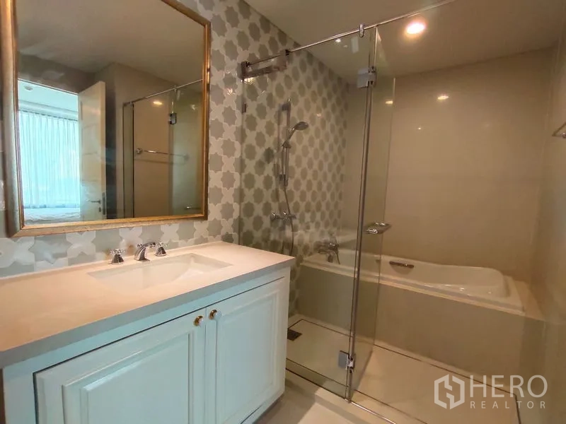 公寓 出租在Khlong Toei, Bangkok - 浴室设玻璃淋浴间、独立浴缸与大镜面，花纹墙砖点缀