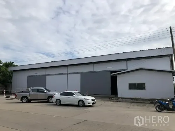 คลังสินค้า ให้เช่าในKhlong Luang, Pathum Thani - ด้านหน้าโกดังสมัยใหม่ ประตูบานสไลด์ขนาดใหญ่ พร้อมลานจอดรถกว้าง.