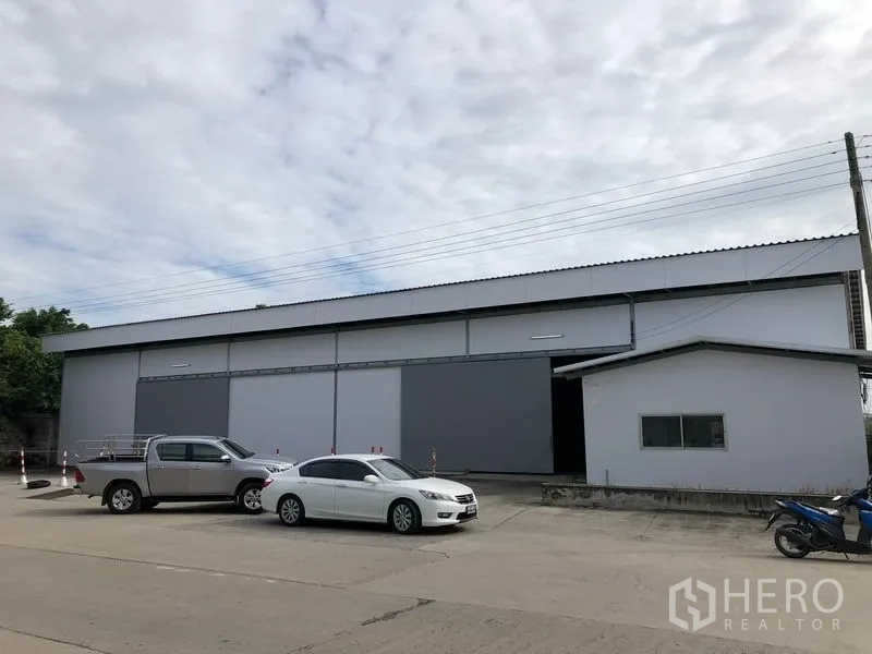 คลังสินค้า ให้เช่าในKhlong Luang, Pathum Thani - ด้านหน้าโกดังสมัยใหม่ ประตูบานสไลด์ขนาดใหญ่ พร้อมลานจอดรถกว้าง.