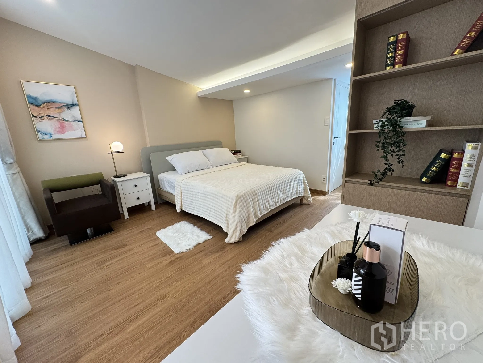 联排别墅 出售 - 卧室带开放式书架、休闲椅与中性色调。