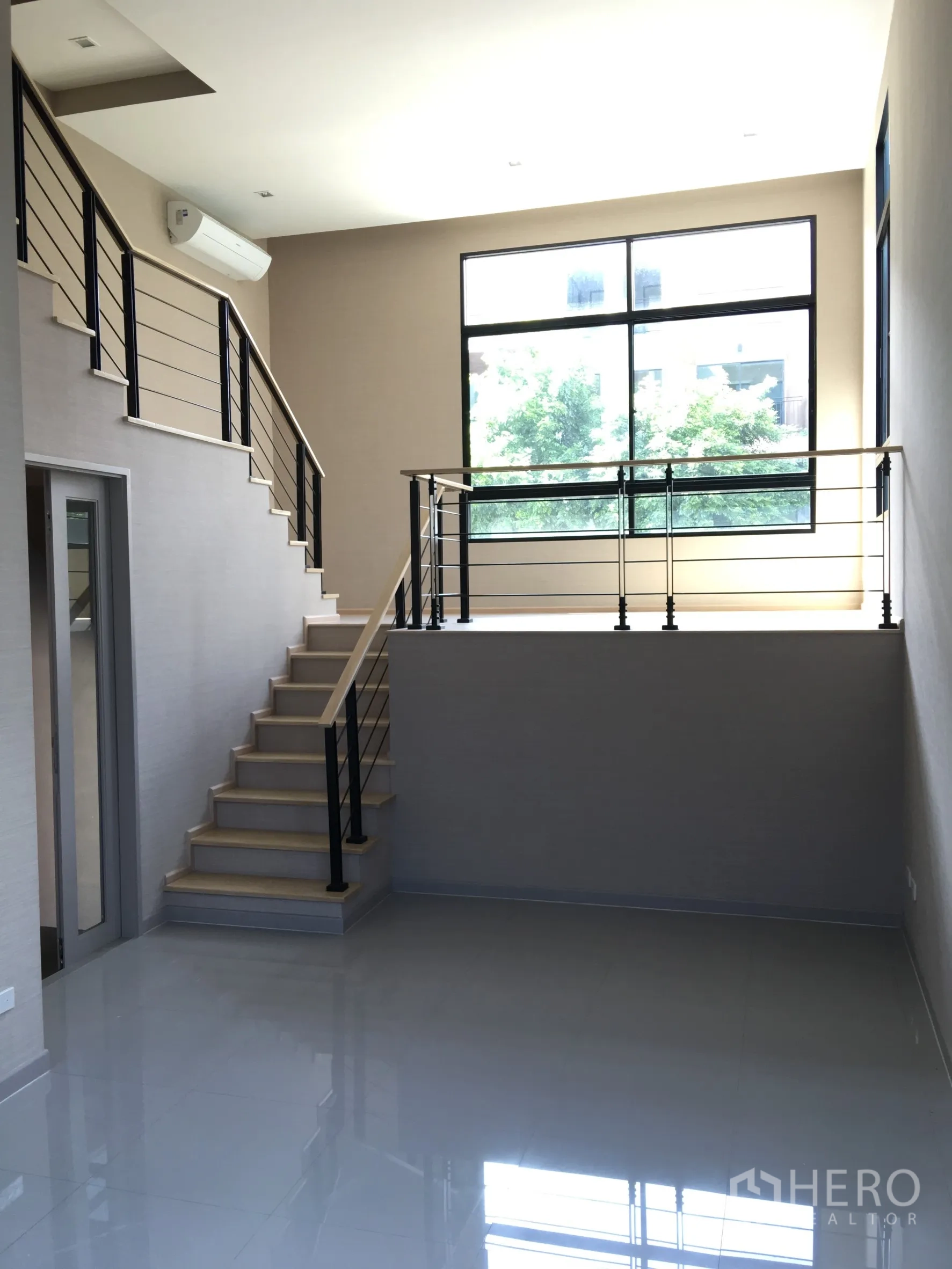 Townhouse for rent or sale in Suan Luang, Bangkok - Bright mezzanine living space with staircase and oversized window.