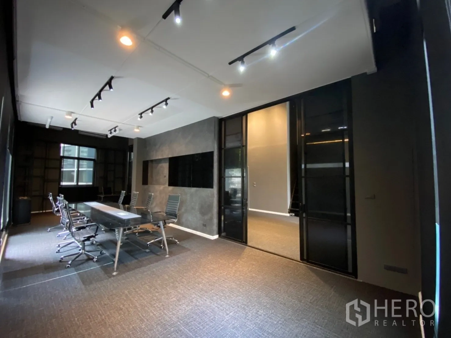 Home Office for rent or sale in Watthana, Bangkok - Meeting room with long conference table, office chairs, and track lighting behind sliding glass doors.