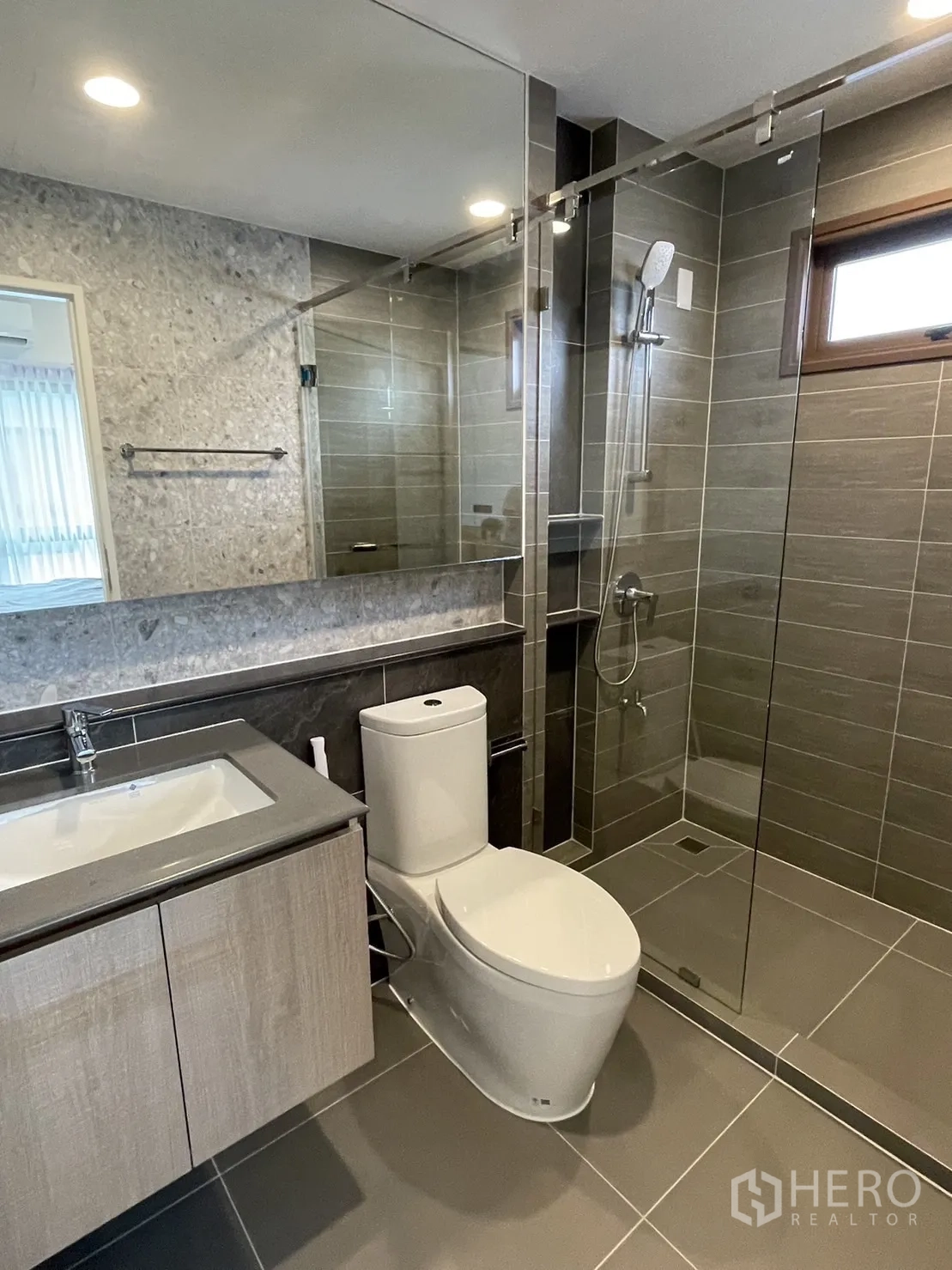 Detached House for rent in Bang Kapi, Bangkok - Contemporary bathroom with glass shower, vanity, and large mirror.