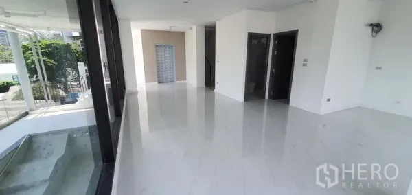 Home Office for rent or sale in Watthana, Bangkok - Open lobby or showroom area with glossy white marble floors and wall‑to‑wall glass.