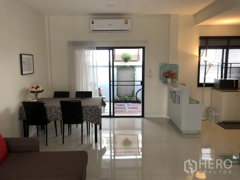 Townhouse for rent in Saphan Sung, Bangkok - Dining area opening to a compact patio through sliding door, glossy tiled floors and wall-mounted AC