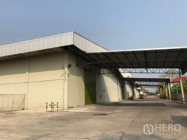 货栈 出租在Bang Pa-in, Phra Nakhon Si Ayutthaya - 仓库立面，多个绿色卷门与连廊雨棚，卡车通道笔直